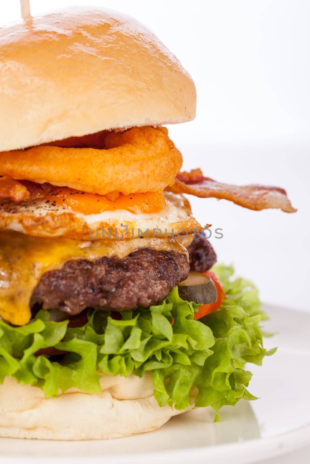Delicious hamburger cheeseburger with bacon egg and salad on a plate isolated on a white background