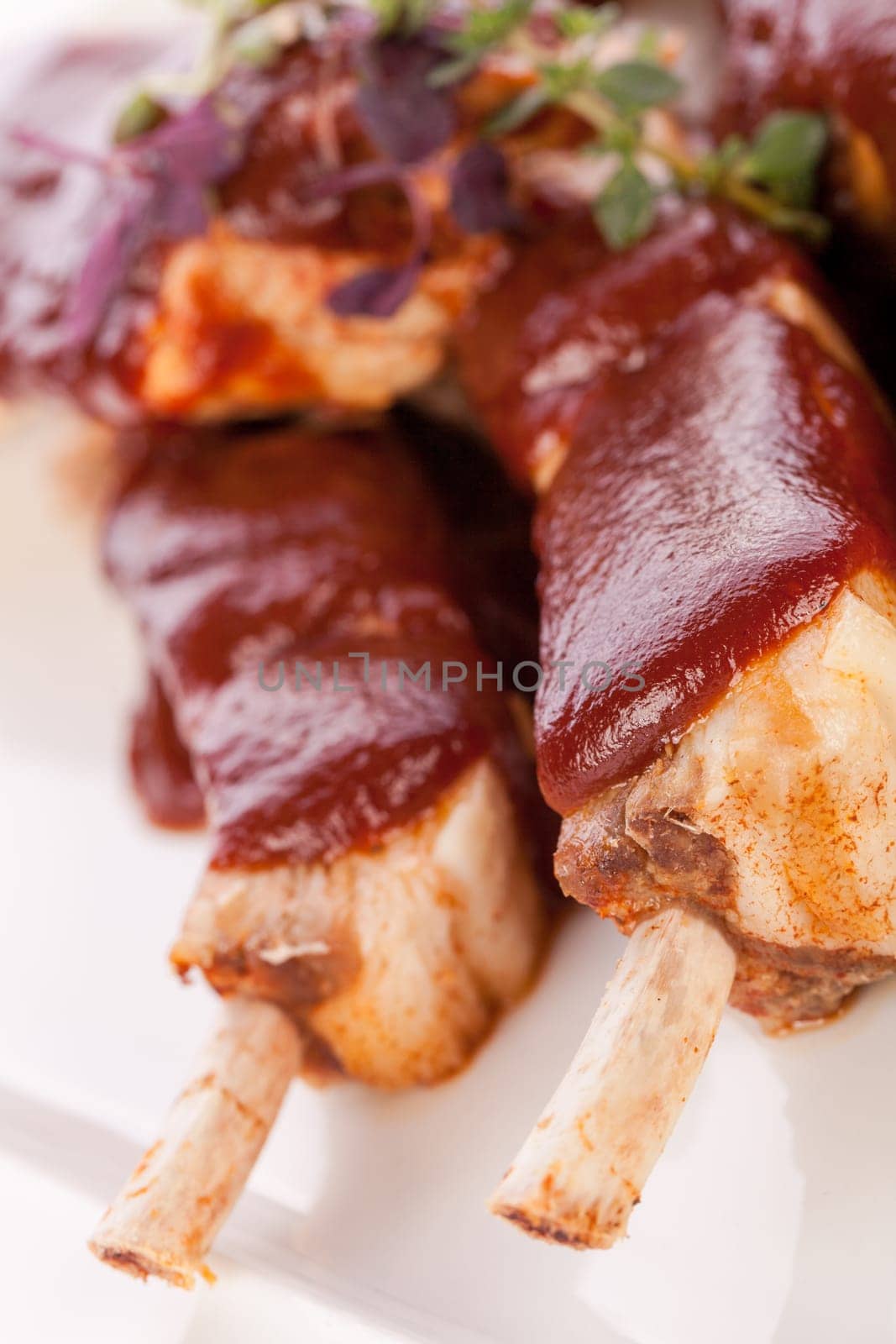 Grilled pork ribs Spareribs with barbecue sauce marinade and herb salad on a plate isolated against a white background