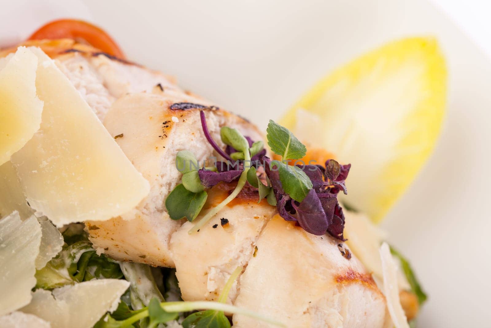 Fresh delicious caesarsalat with grilled chicken bust parmesan shards and croutons isolated against a white background