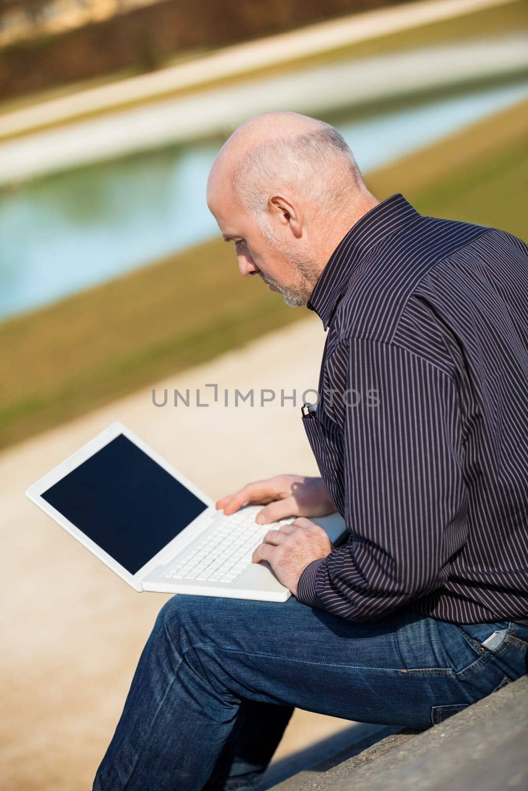 Businessman senior with notebook laptop during lunch break in summer outdoors