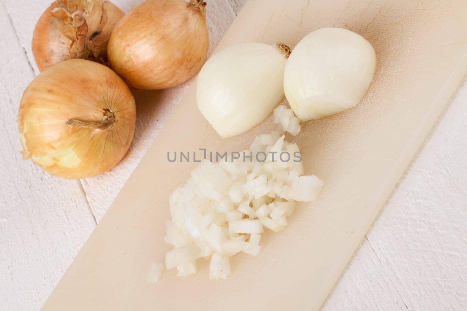 White and red onions peeled and with slurs as a whole and in cubebrunoise as a close-up on cutting board