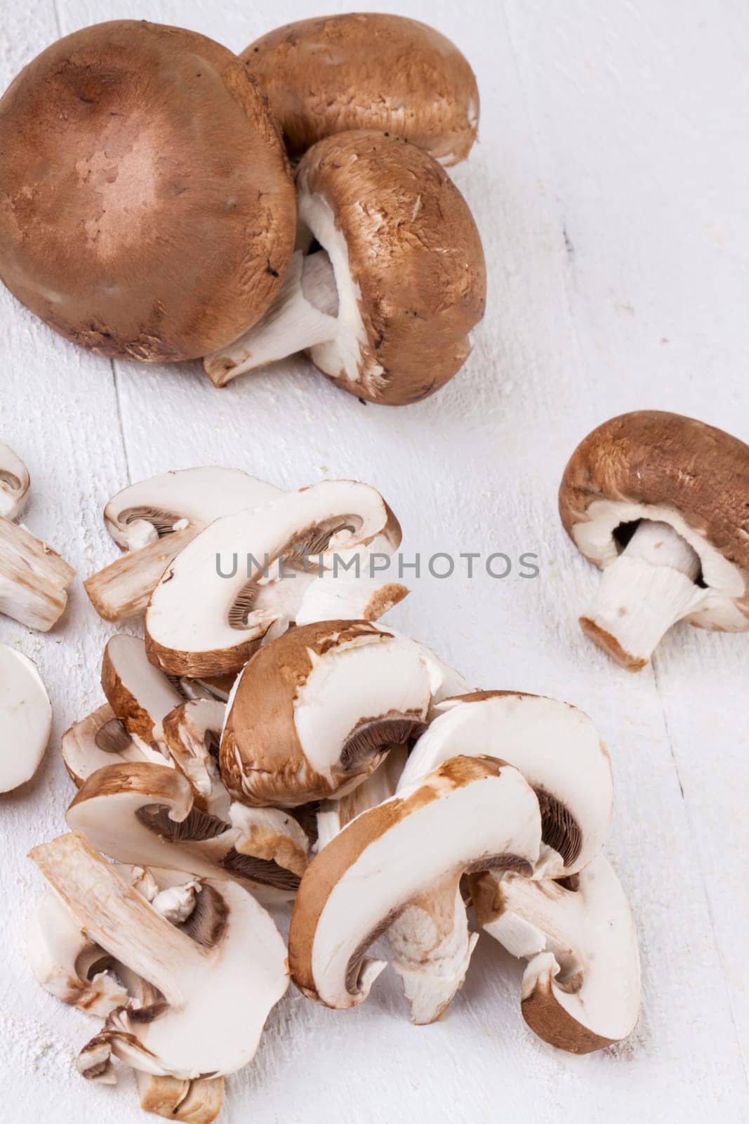 Fresh stone mushrooms Champiggnons whole and sliced on a white wooden board