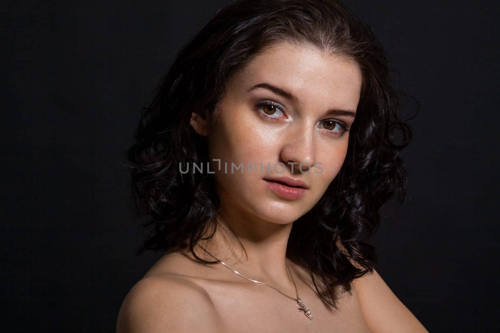 Young attractive woman with freckles in portrait against a black background