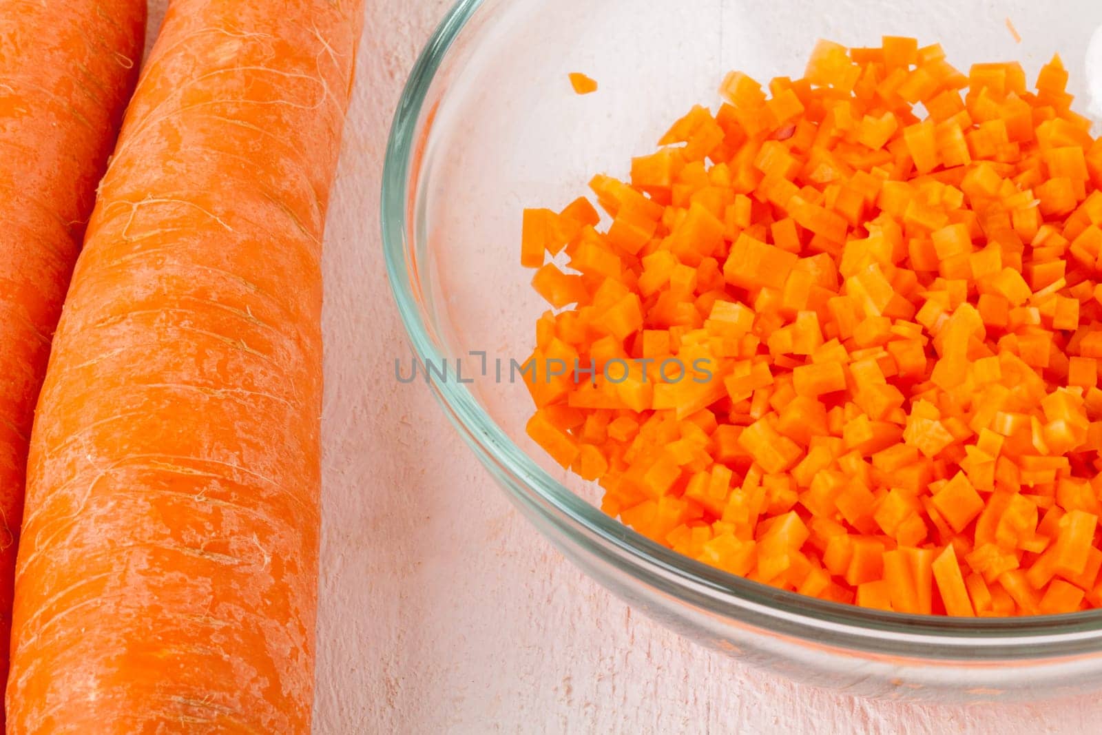 Fresh carrots beet root beet as whole and finely diced brunoise in a bowl on a white wooden board