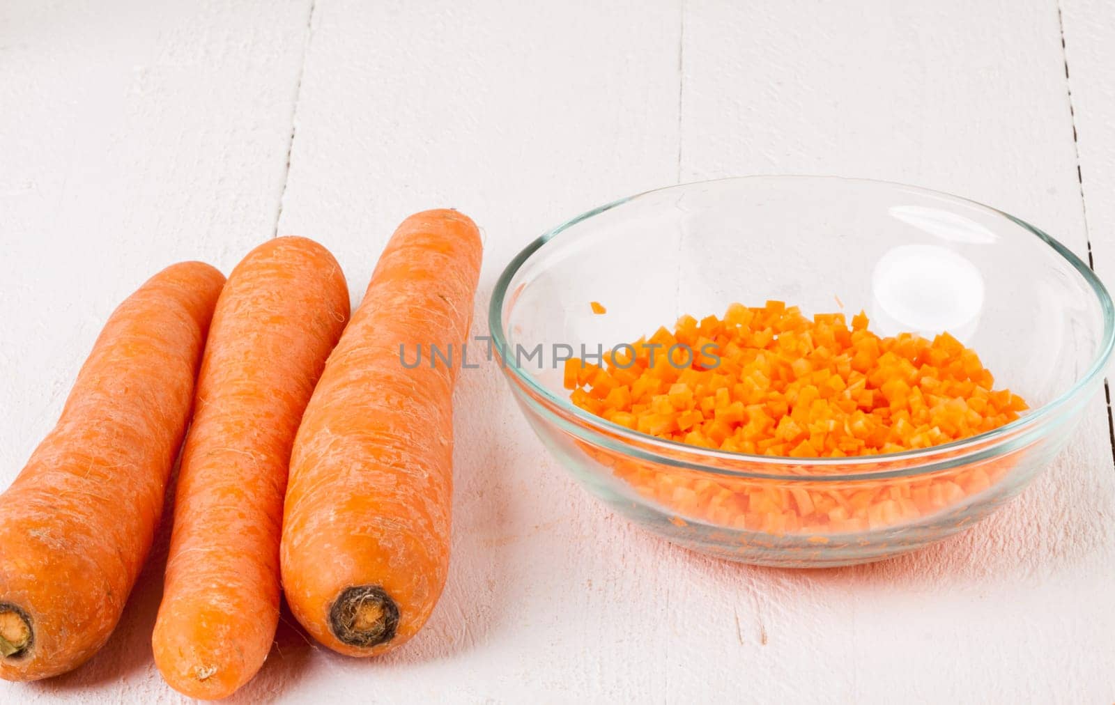 Fresh carrots beet root beet as whole and finely diced brunoise in a bowl on a white wooden board
