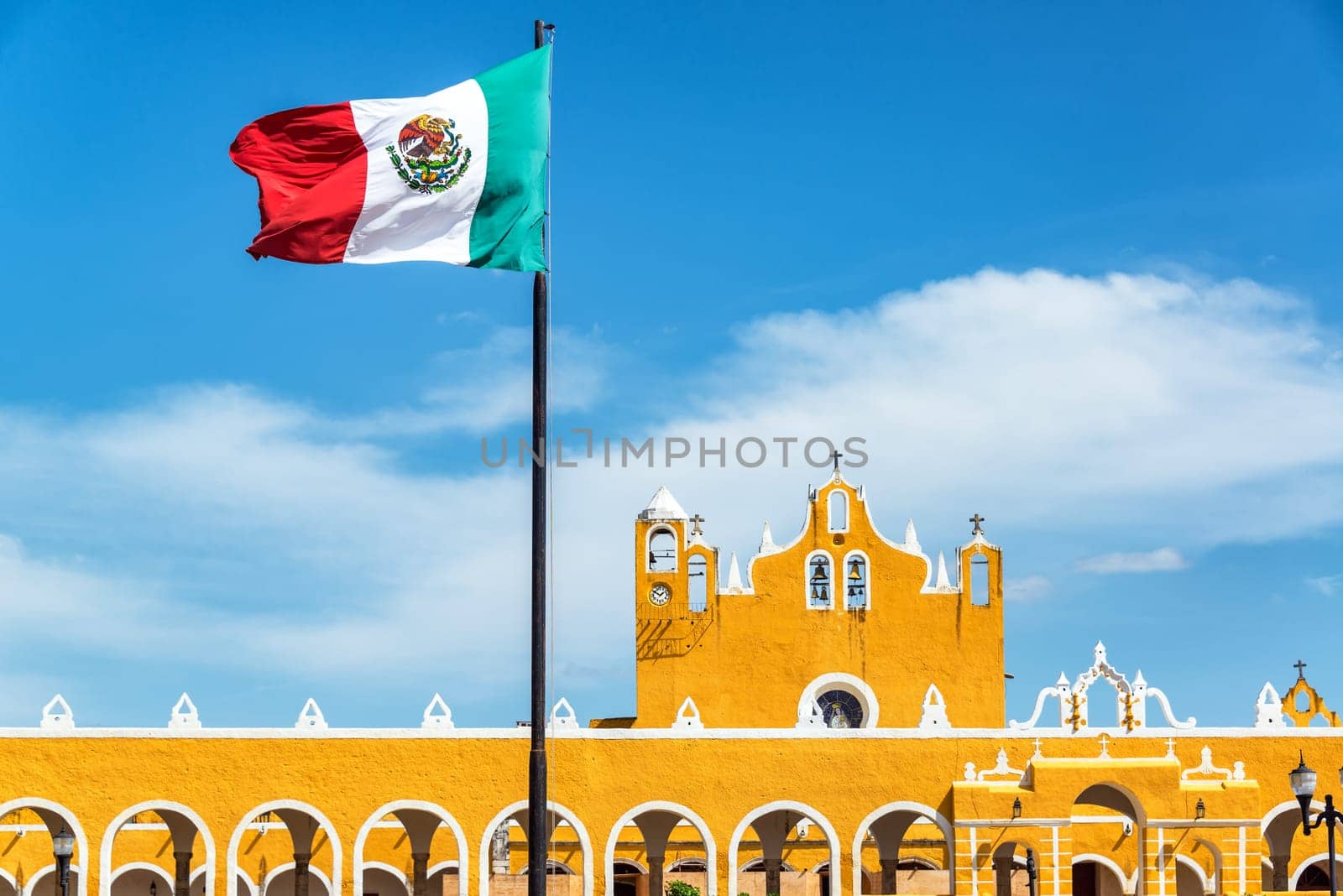 Yellow colonial monastery in Izamal, Mexico with the Mexican flag flying above