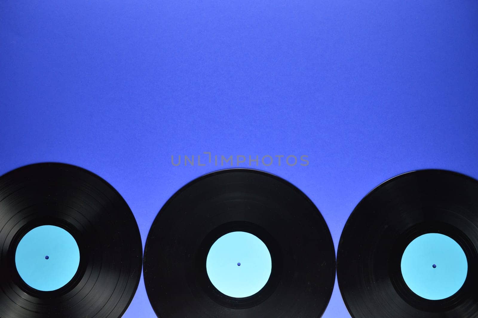 border of old black vinyl records with blank cyan labels on blue background