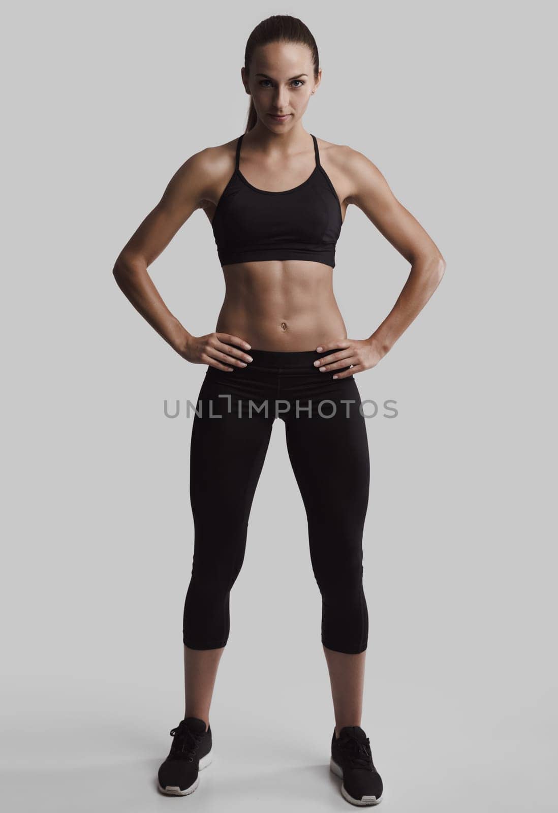 Portrait of sporty young woman with muscular body looking at camera