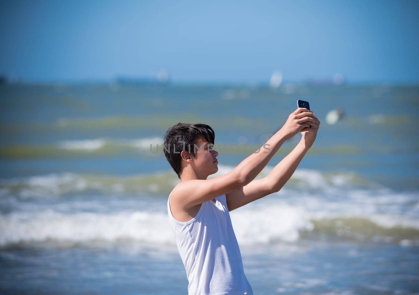 SCHEVENINGEN, NETHERLANDS - JULY 3, 2016: Unknown boy making a selfie for his girlfriend along the sea shore