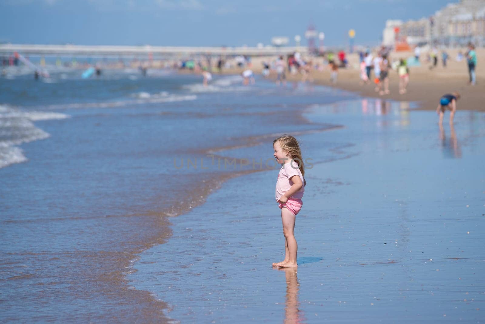 SCHEVENINGEN, NETHERLANDS - JULY 3, 2016: Unknown little girl enjoying the waves at the North sea beach