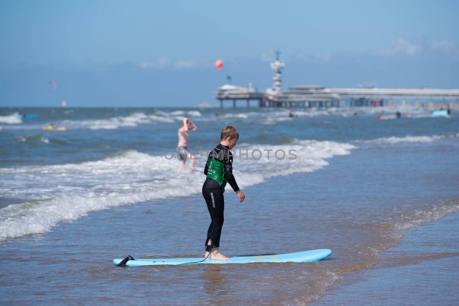 SCHEVENINGEN, NETHERLANDS - JULY 3, 2016: Unknown boy learning to ride on his surfboard at the dutch north sea coast