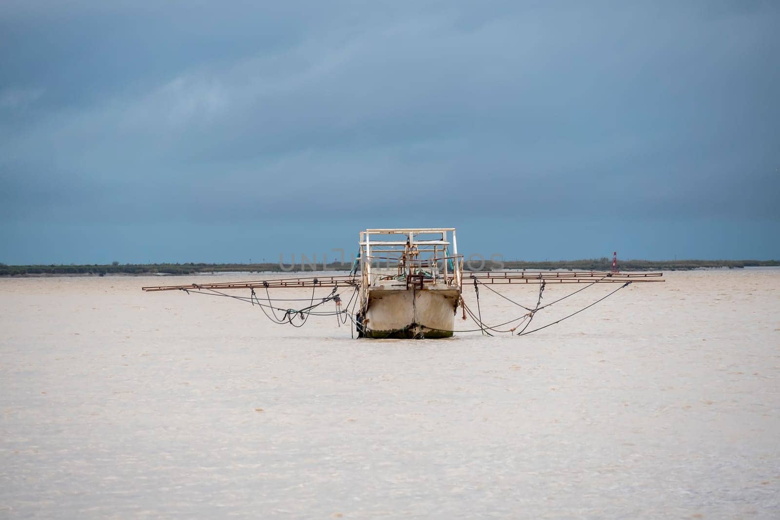 Fishing boat moving through the river on cloudy day