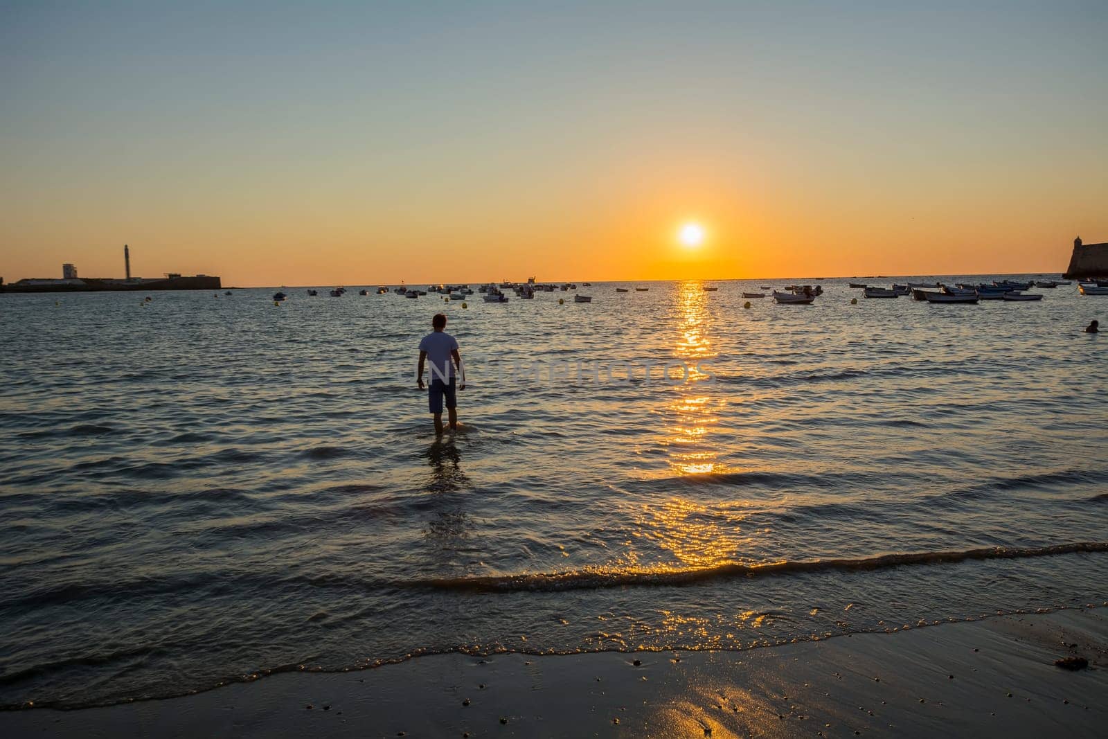 Young boy licking their feet on the beach at sunset