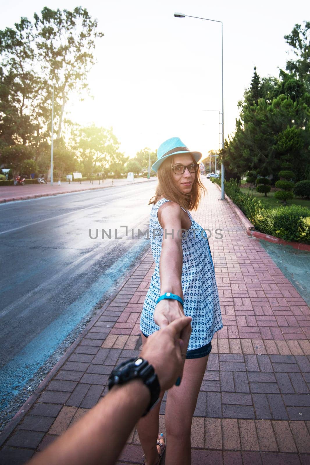 Beauty woman in blue hat holding man by hand and going around the Alanya city in Turkey