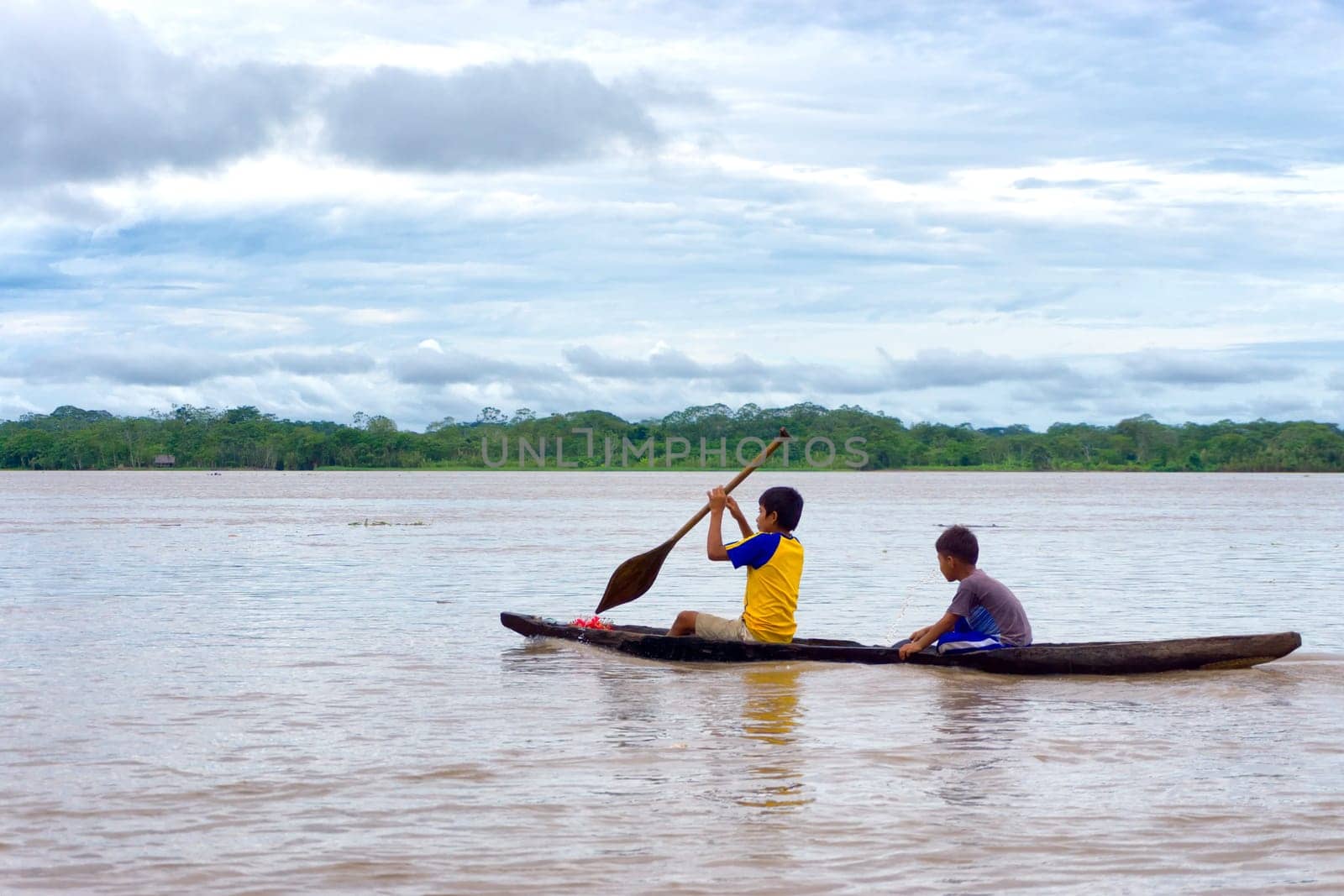 IQUITOS, PERU - MARCH 13: Two children navigate the Amazon River in a dugout canoe near Iquitos, Peru on March 13, 2015