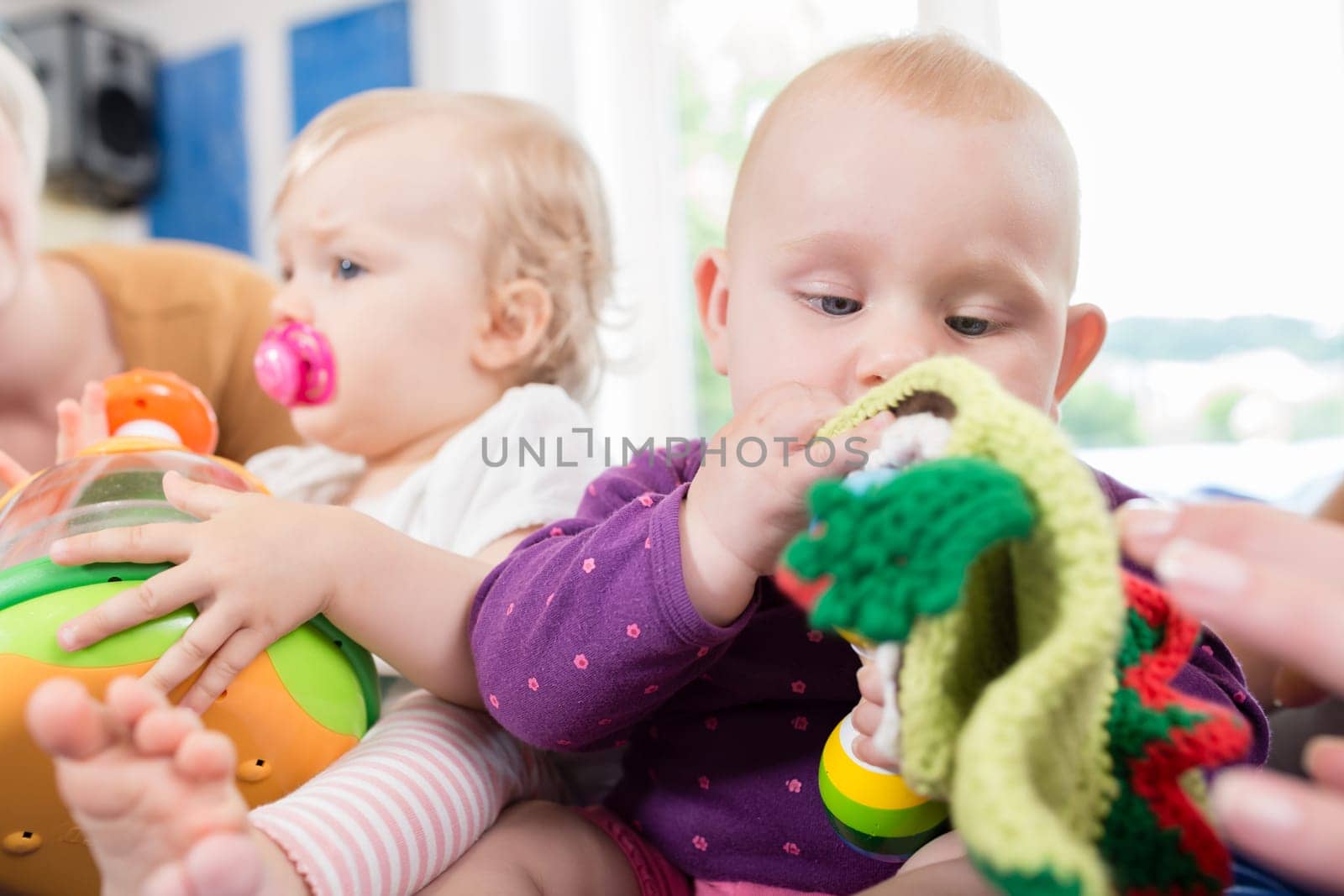 Babies with pacifier in toddler group playing with toys