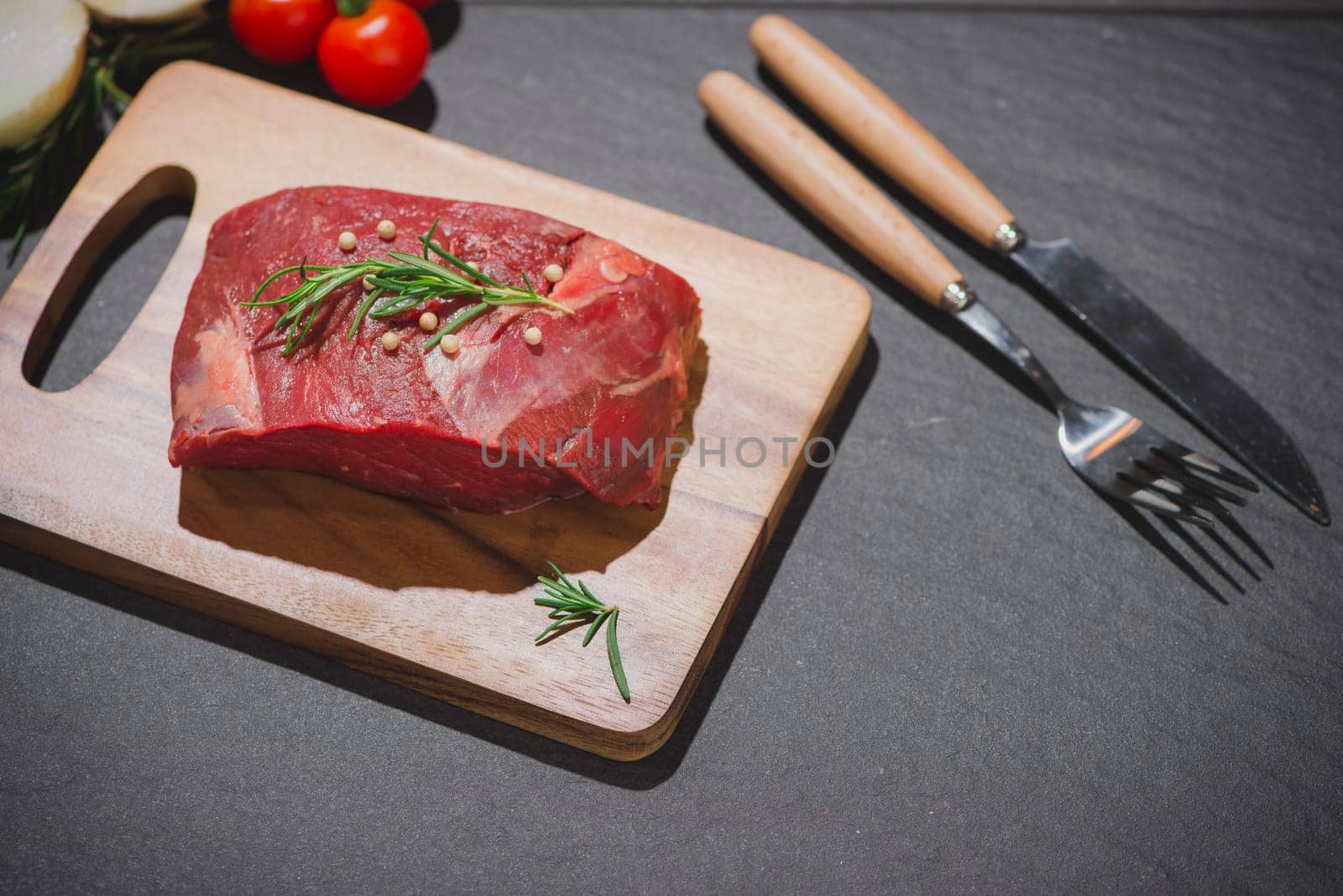 Raw beef on a cutting board  with spices and ingredients for cooking.