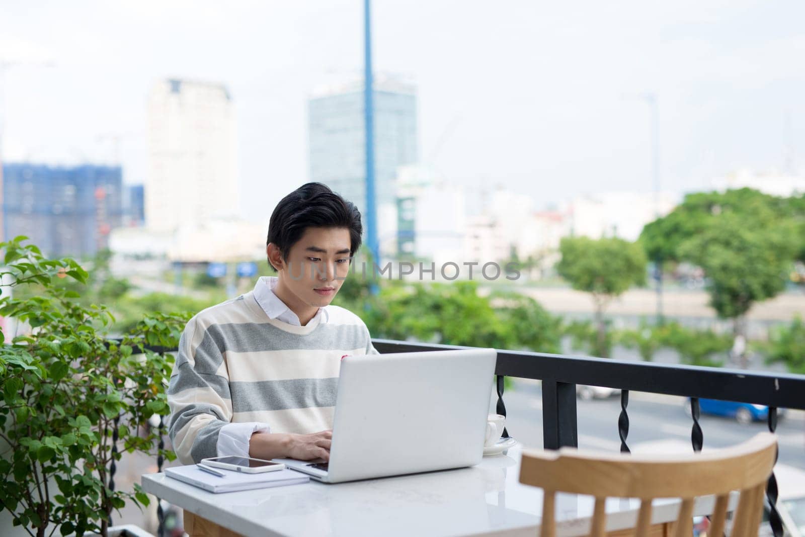 Asian young business man working with laptop at the city cafe.