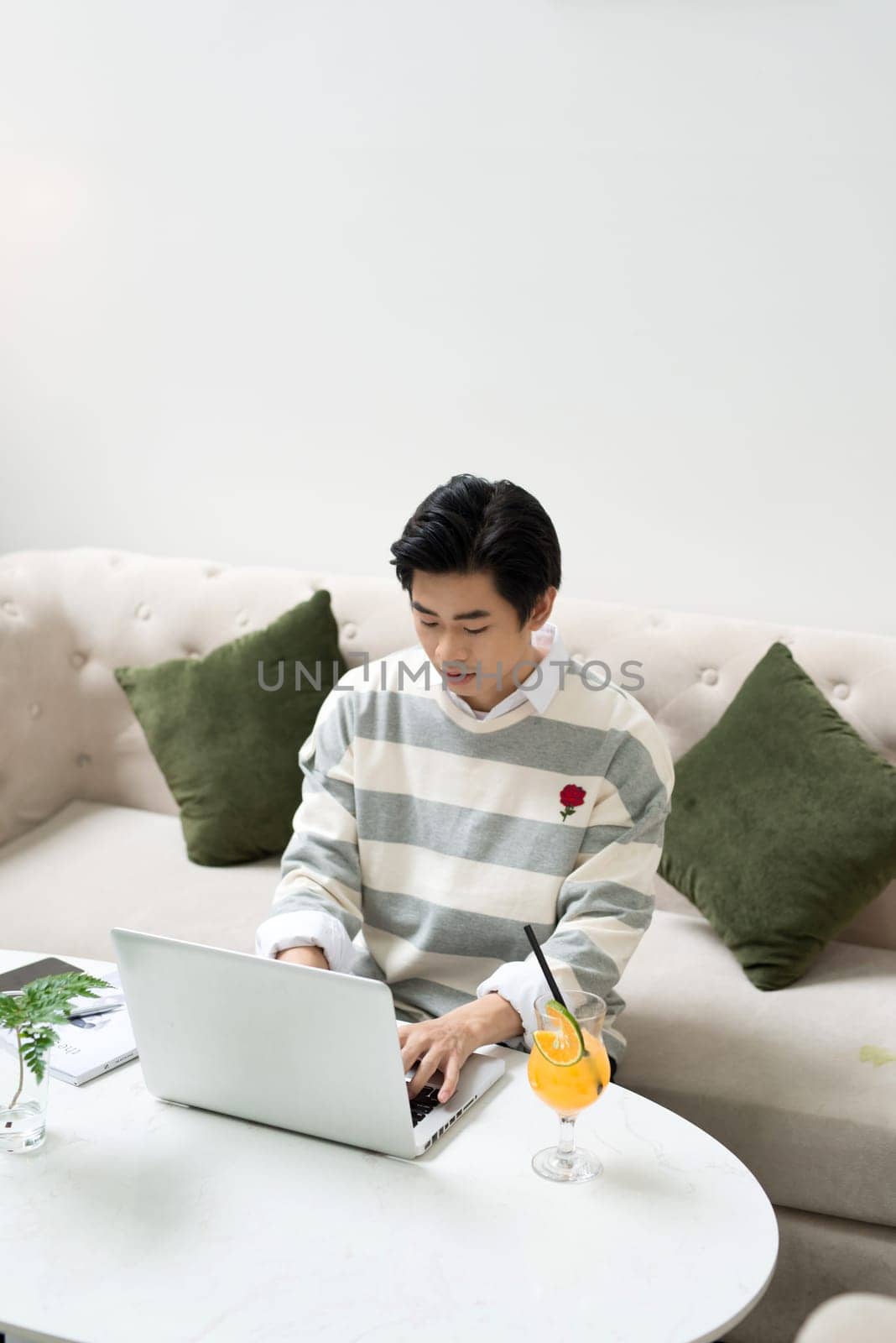 Asian young businessman working on his laptop in a coffee shop