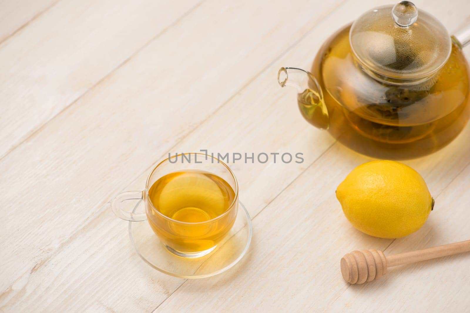 Cup of lemon tea with honey on white wooden background.