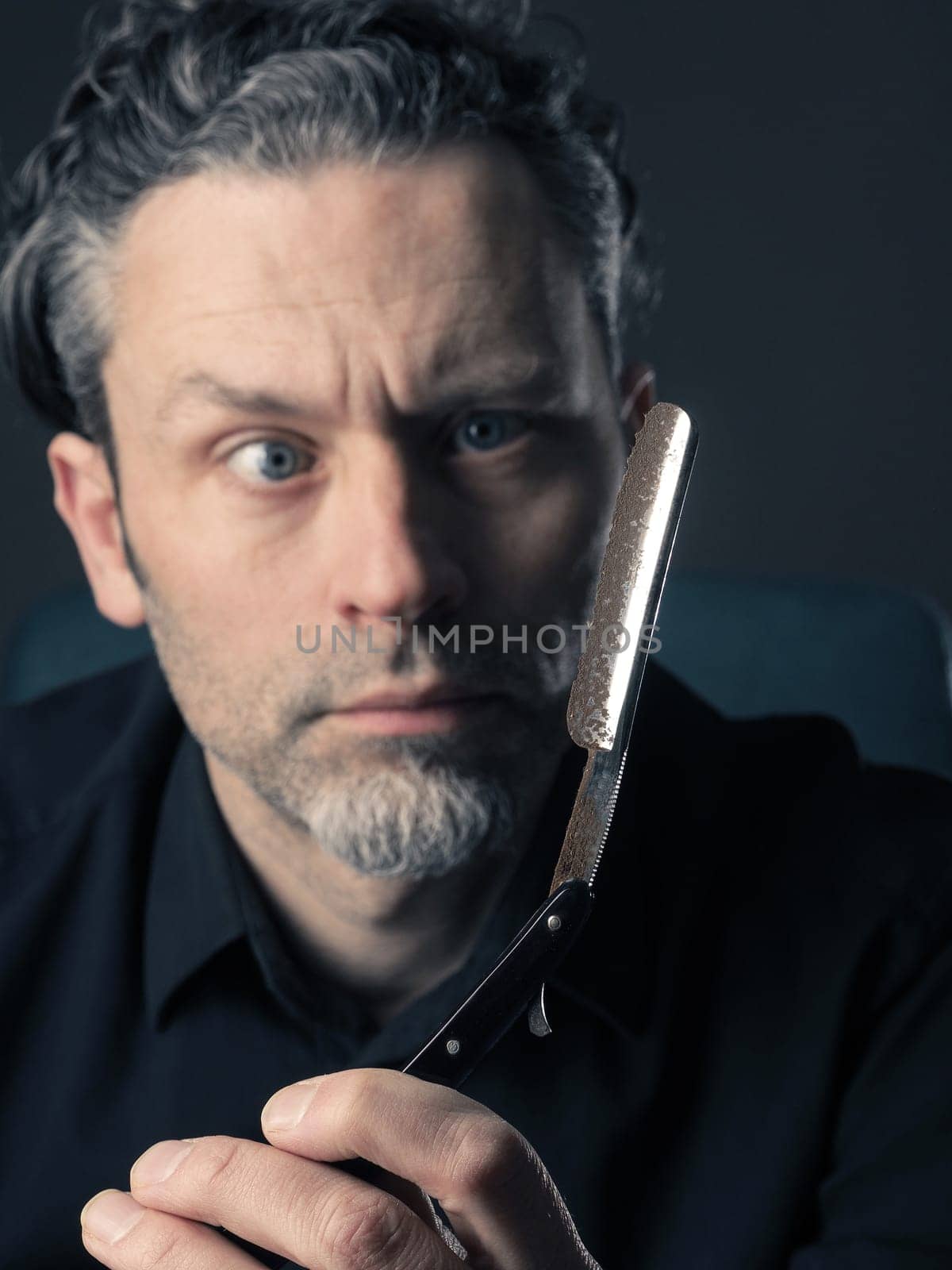 Handsome man with a rusty old shaving knife looking scary