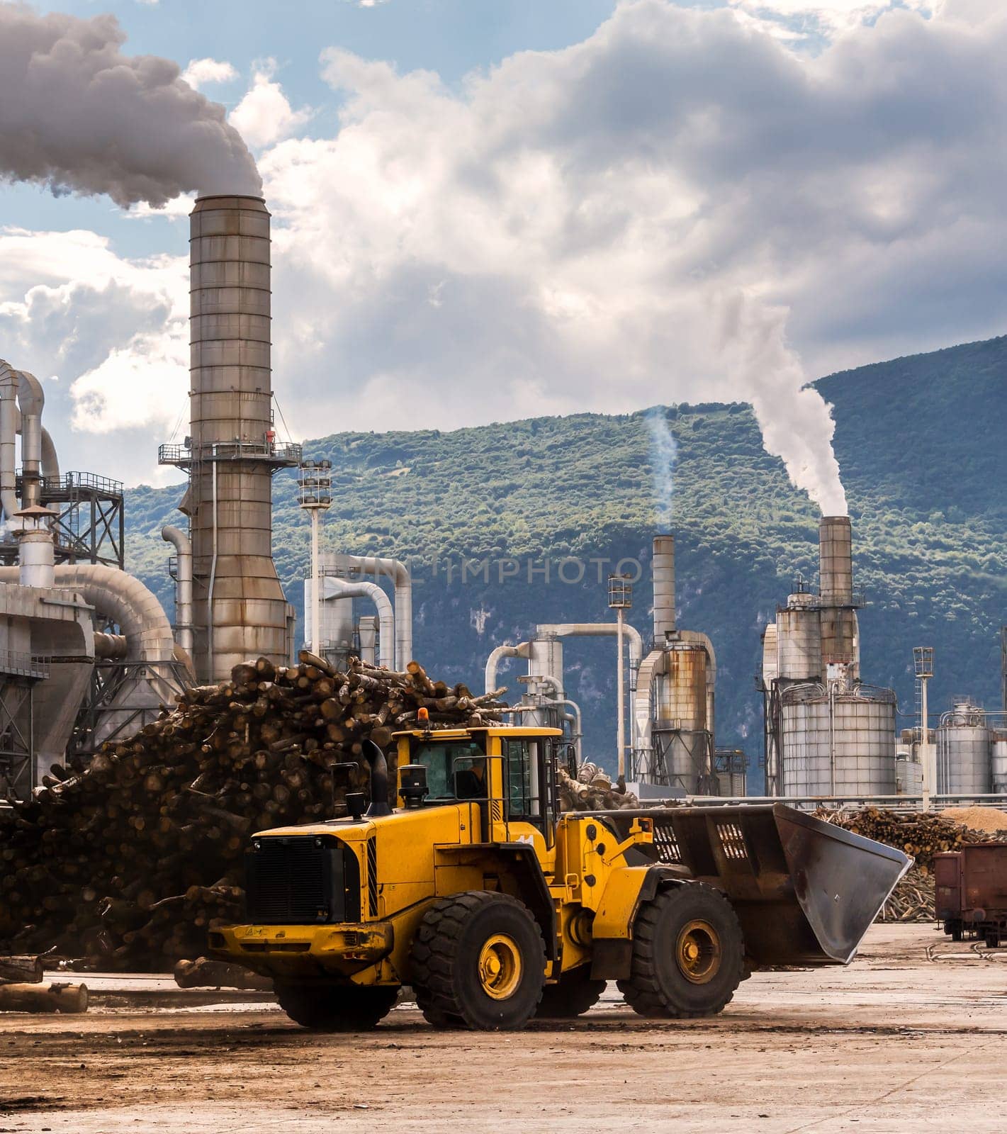 Industrial scene. Excavator ,smokestack,silos and rail wagon of lumber factory.
