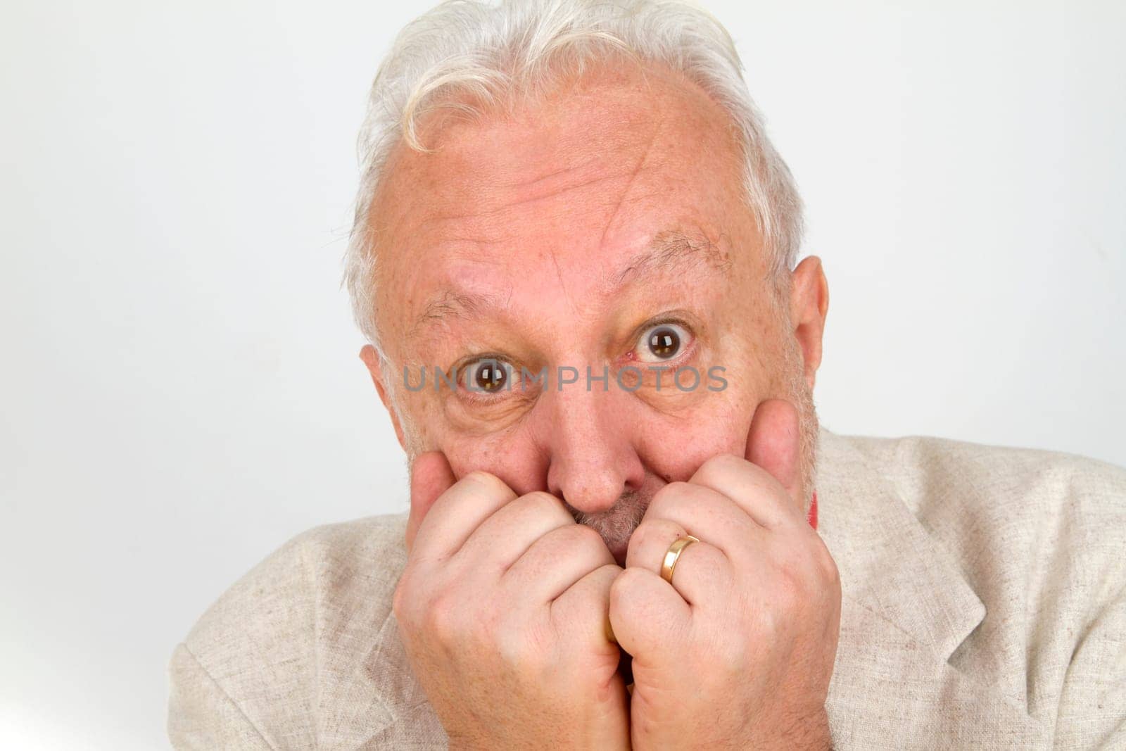 Senior holds hands in front of his mouth - on a bright background