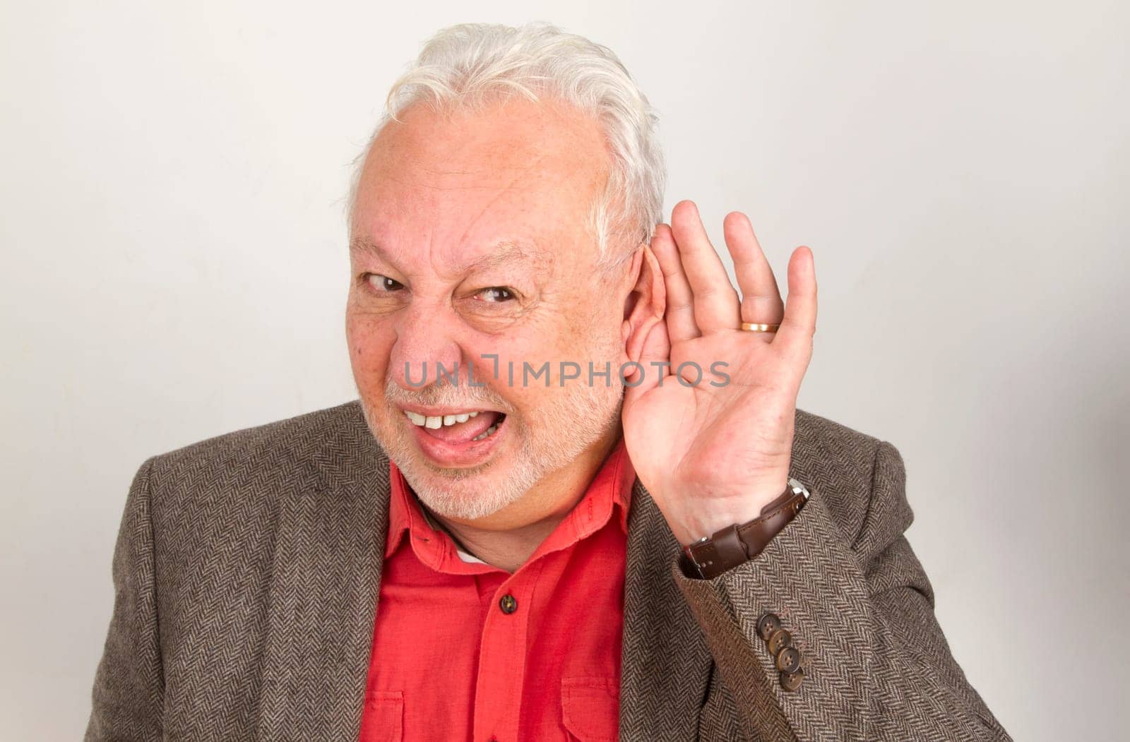Hearing impaired senior holds hand to ear on a bright background