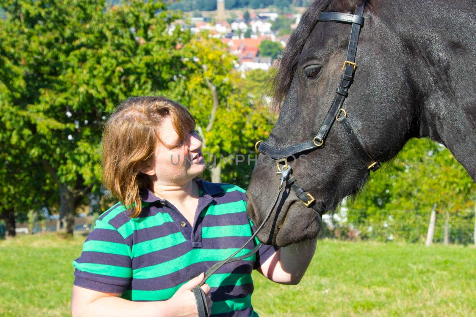 Young woman with Frisian horse in a summer landscape
