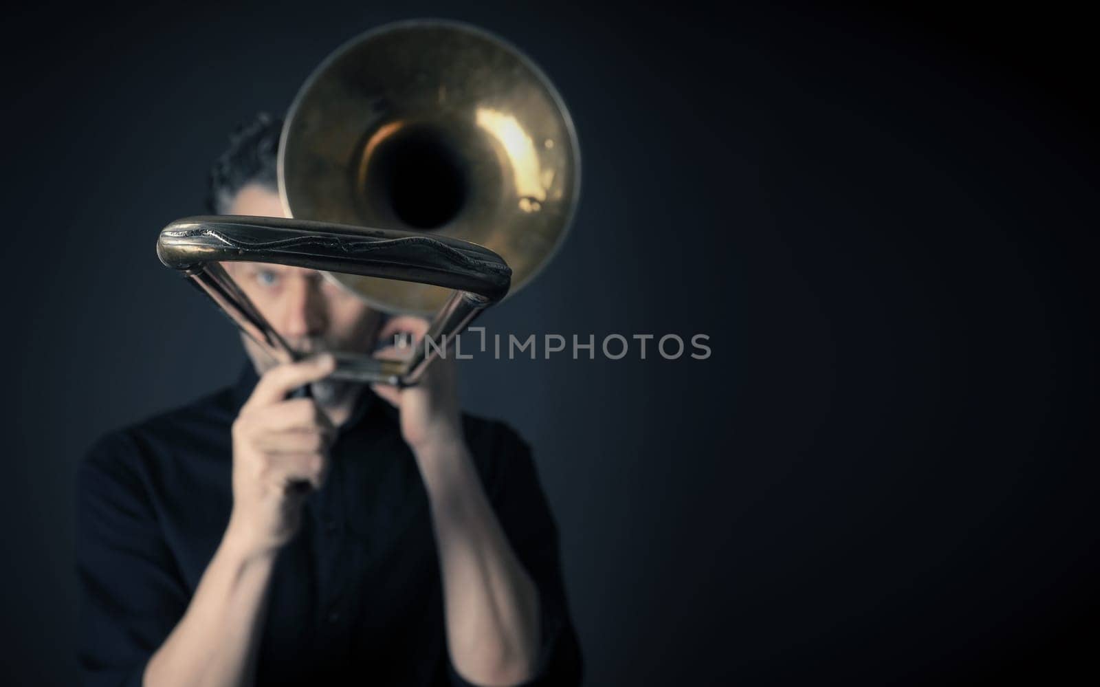 Dark portrait of a musician with a trombone, selective focus and space for text