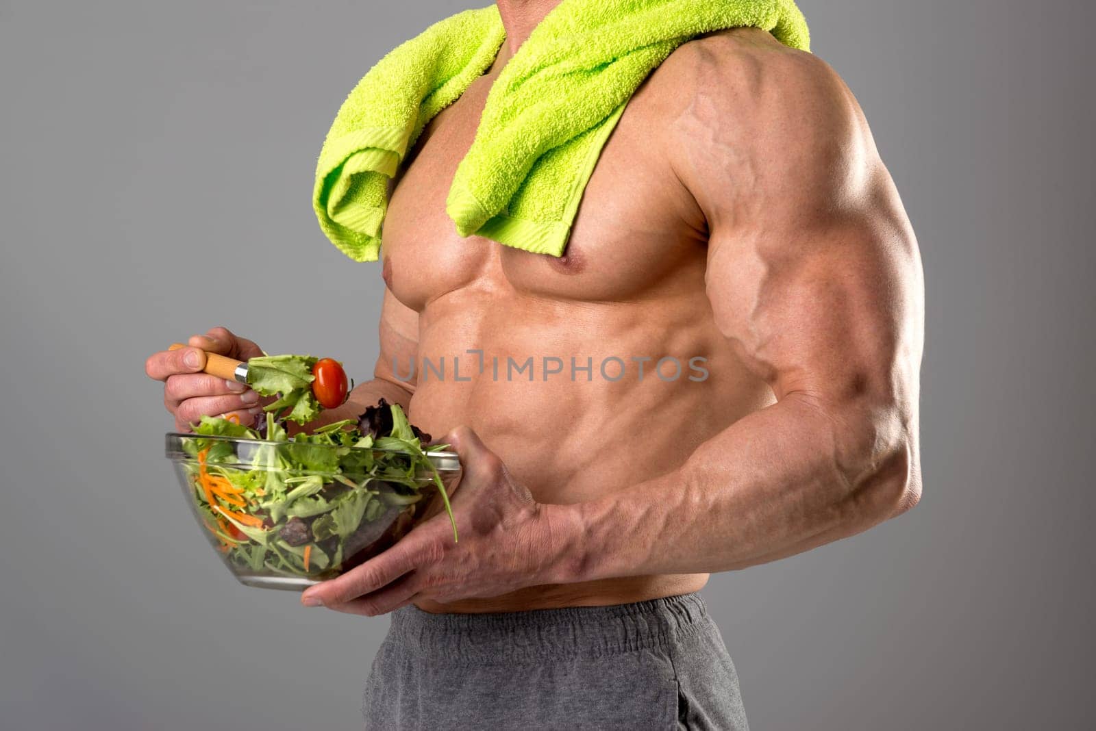 Powerful athletic man with great physique eating a healthy salad.
