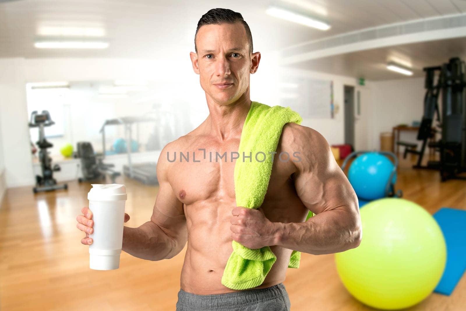 Powerful athletic man with great physique holding a gym bottle
