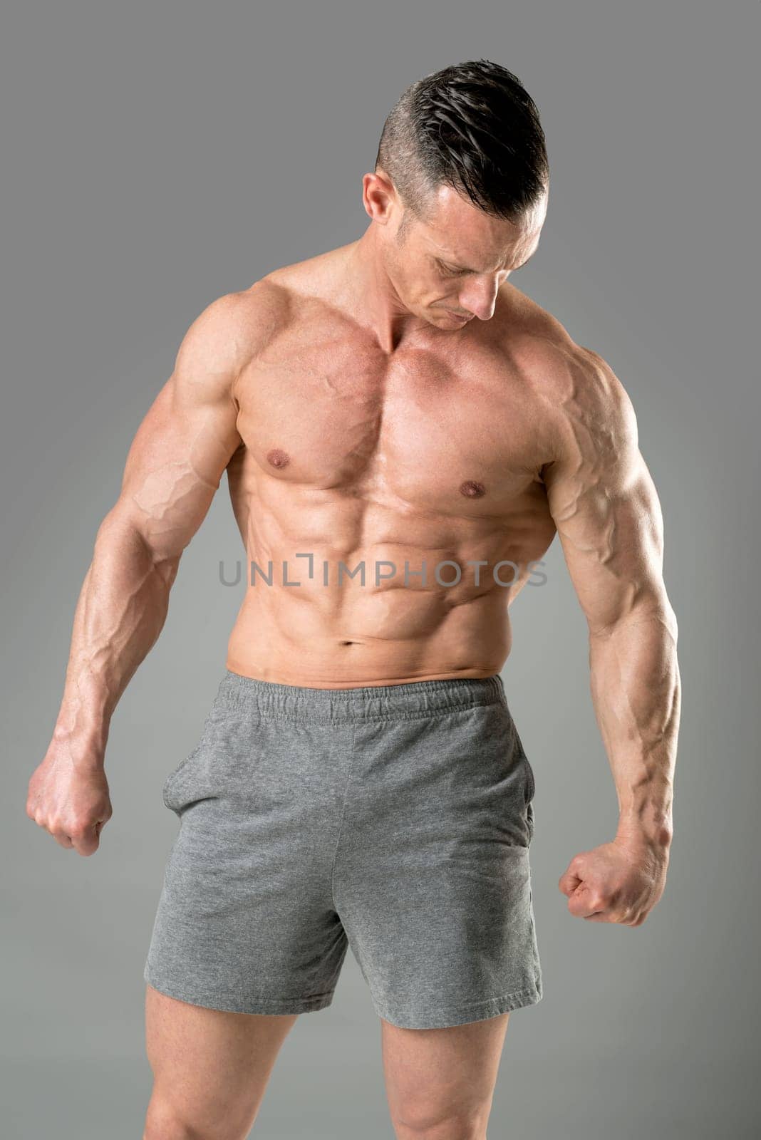 Powerful athletic man with great physique. Strong bodybuilder with six pack, perfect abs, shoulders, biceps, triceps and chest.