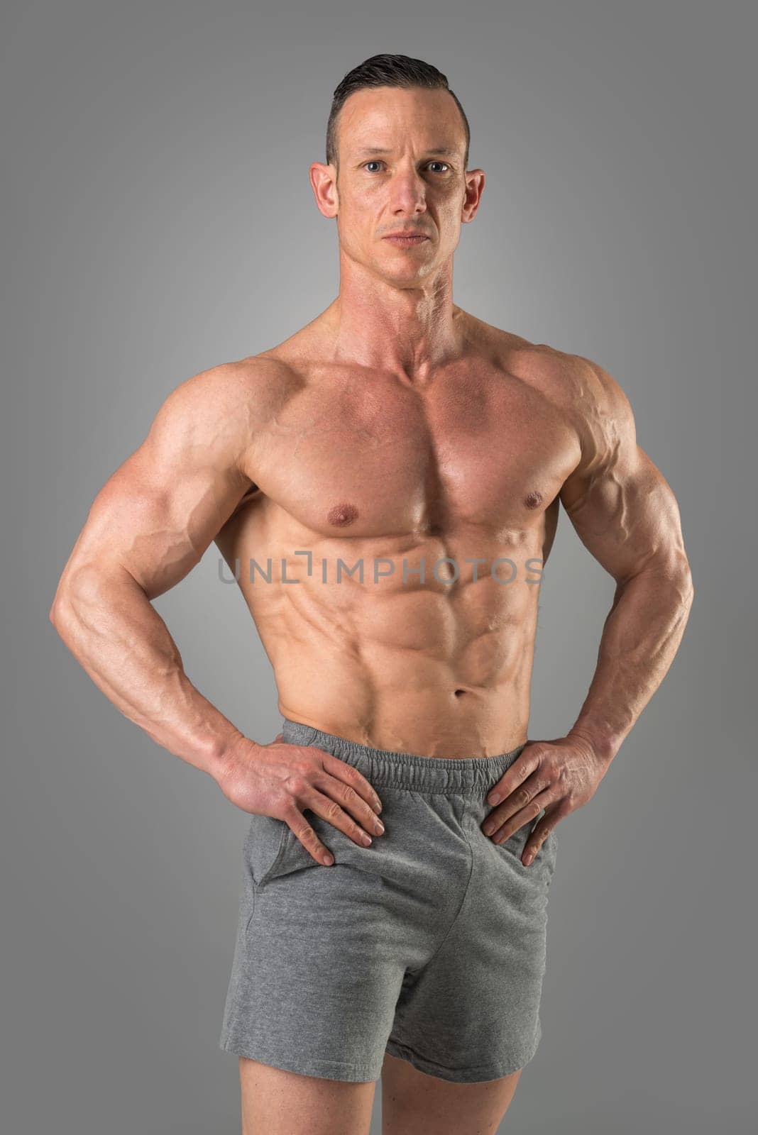 Powerful athletic man with great physique. Strong bodybuilder with six pack, perfect abs, shoulders, biceps, triceps and chest.