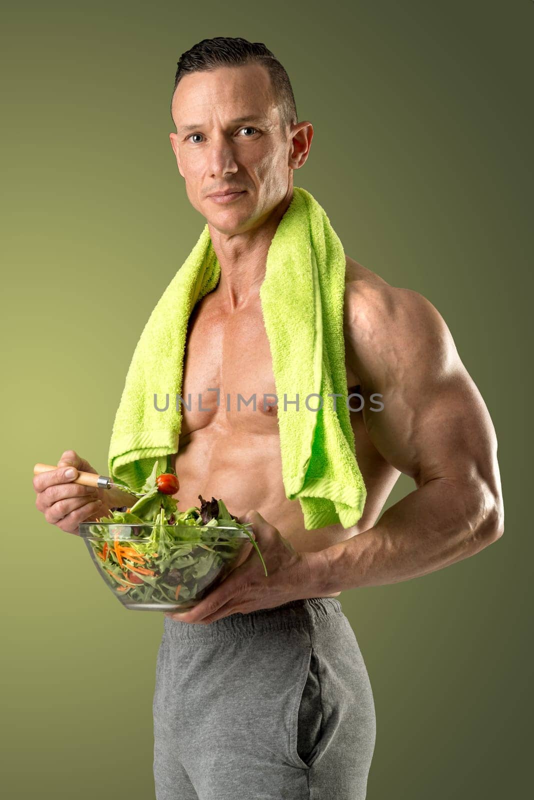Powerful athletic man with great physique eating a healthy salad.
