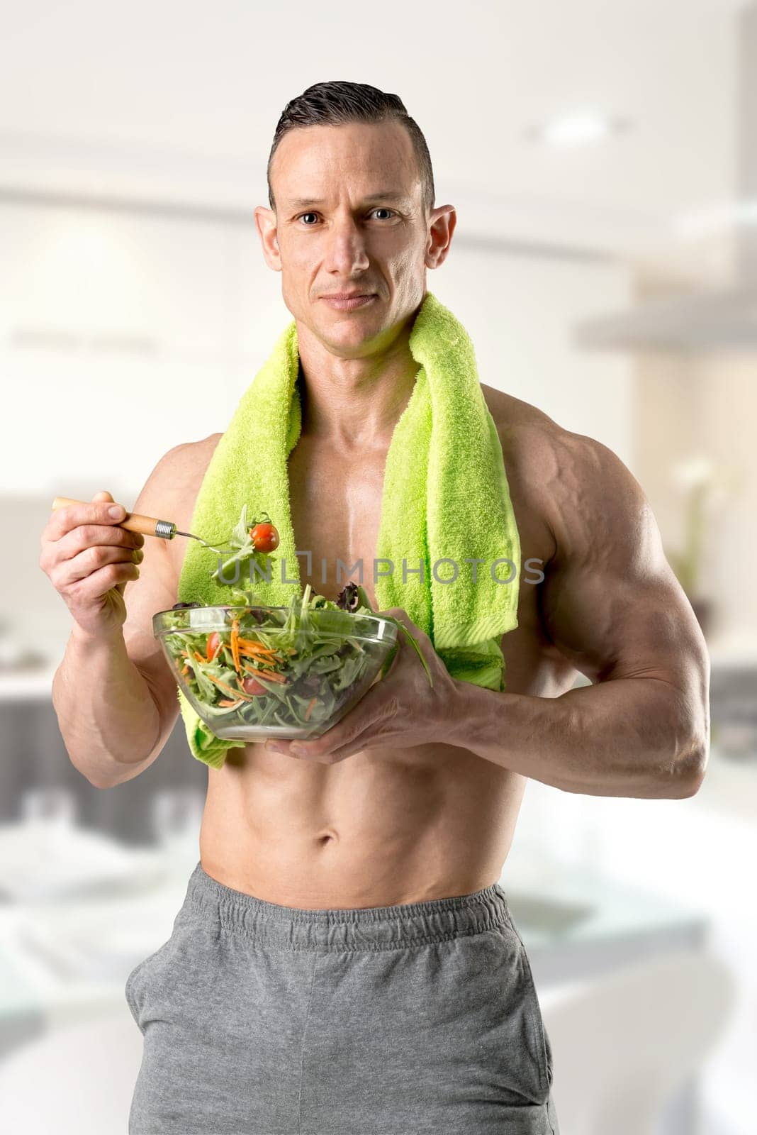 Powerful athletic man with great physique eating a healthy salad.