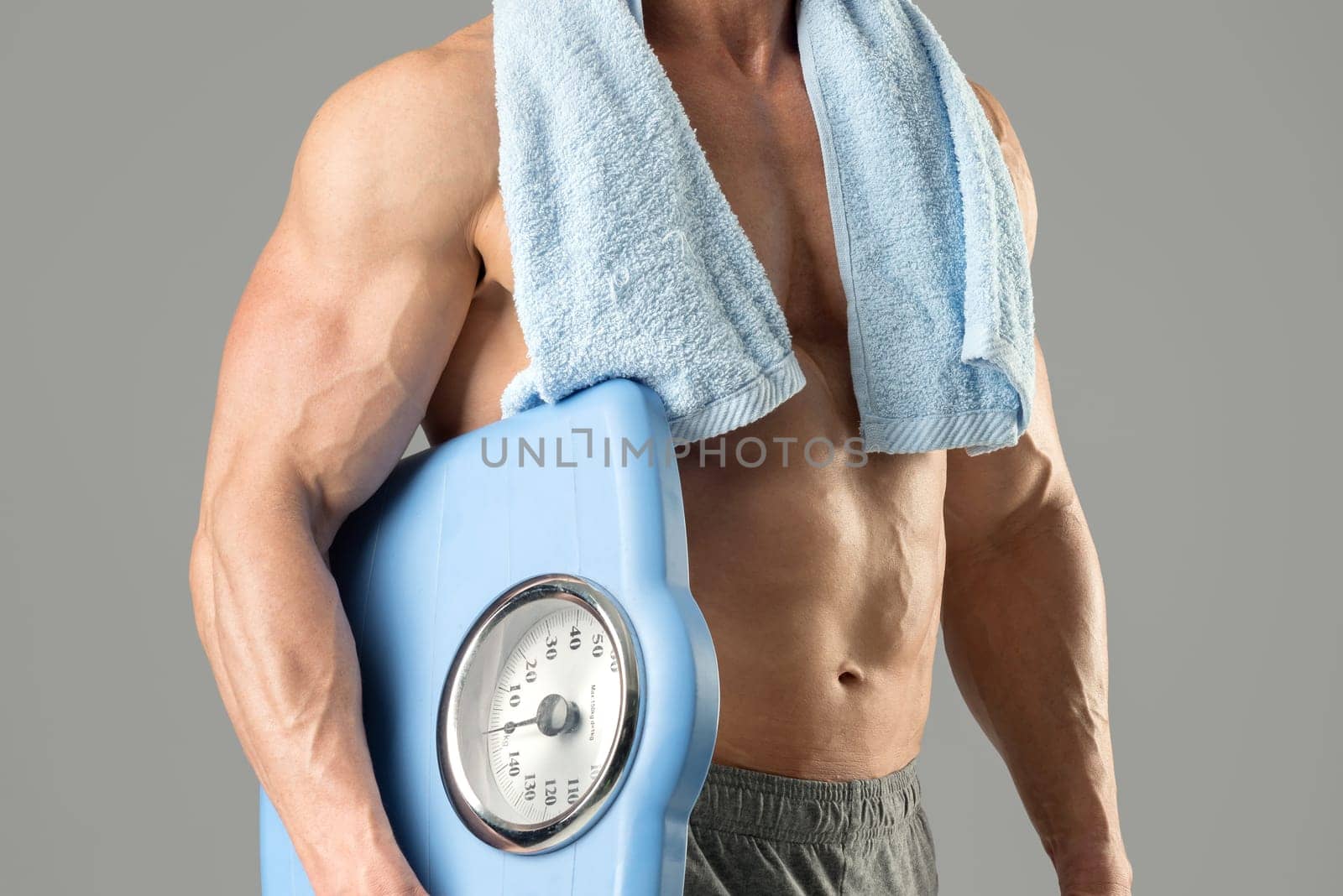 Powerful athletic man with great physique holding a weight scale.