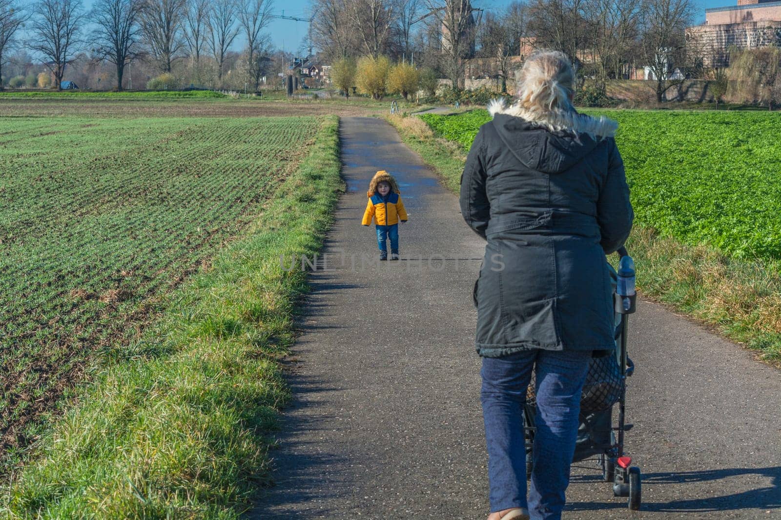 Grandmother with grandson walking and pushing a stroller..