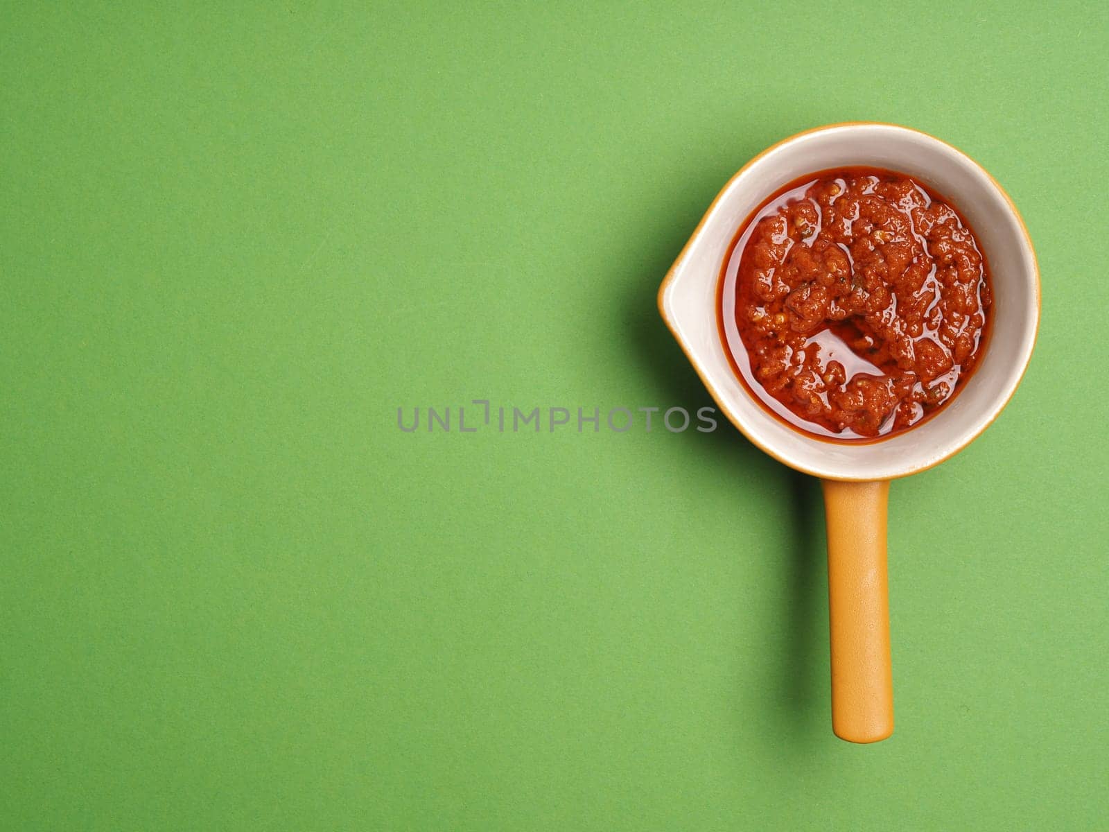 Red pesto on green background, italian food concepts, view from above