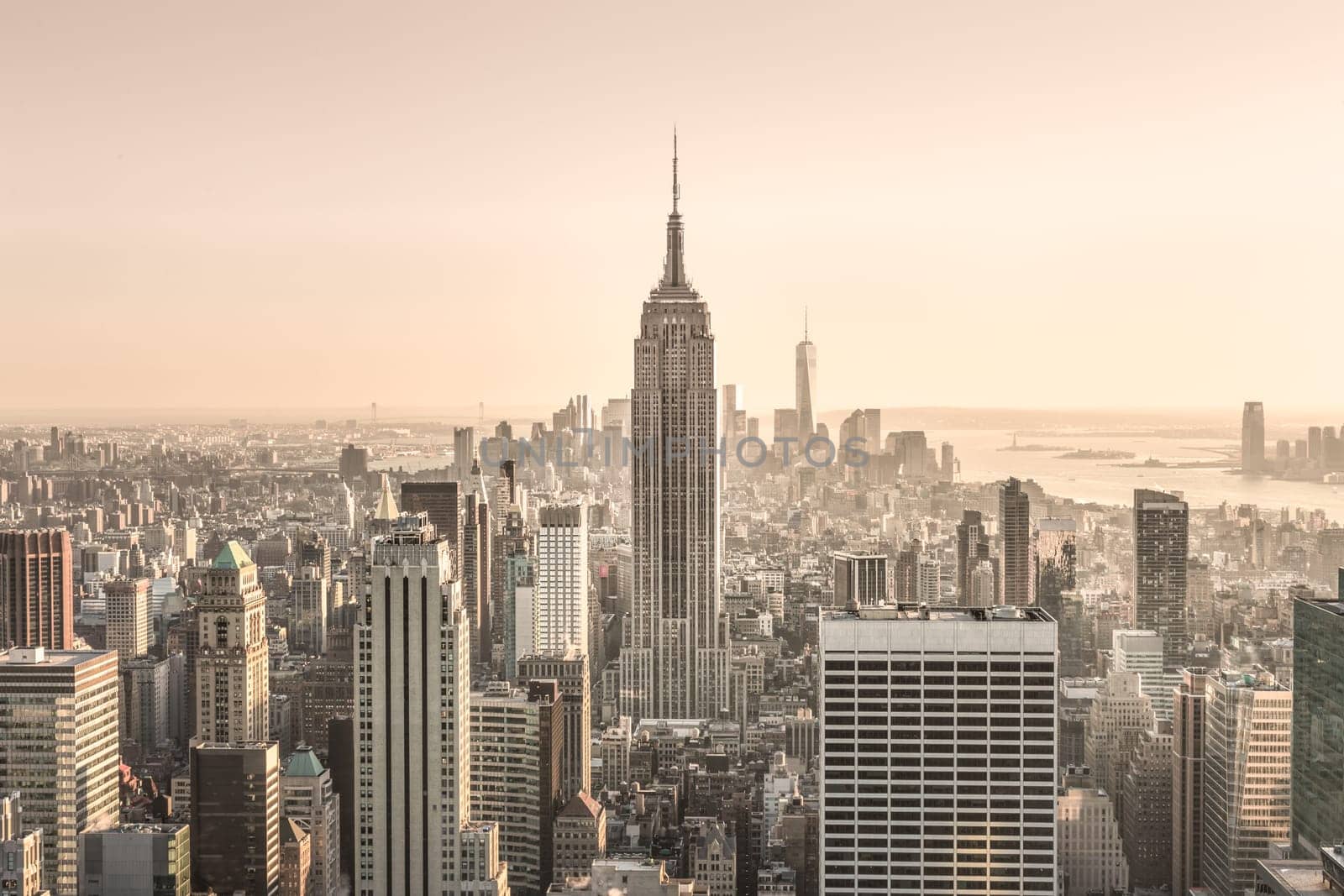 New York City. Manhattan downtown skyline with sun illuminated Empire State Building and skyscrapers at sunset.