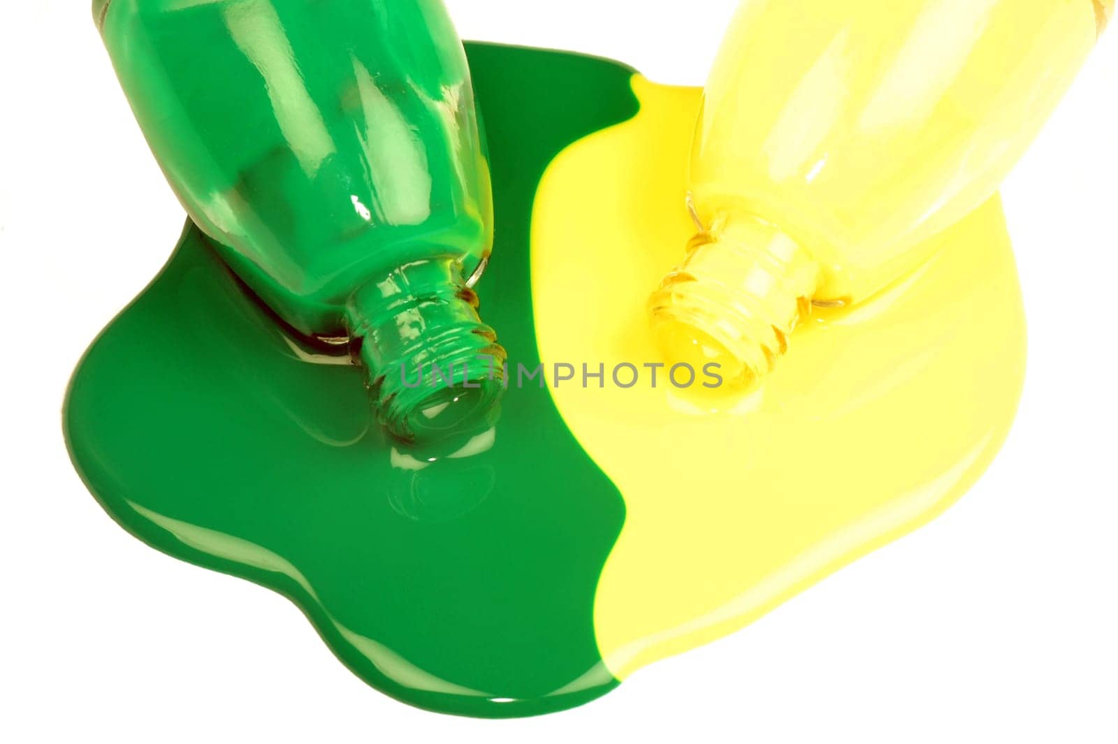 The spilled green and yellow nail polishes are on white background.