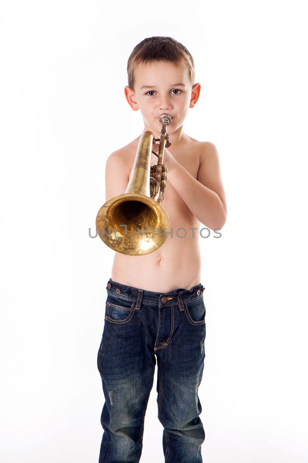 young boy blowing into a trumpet against white background
