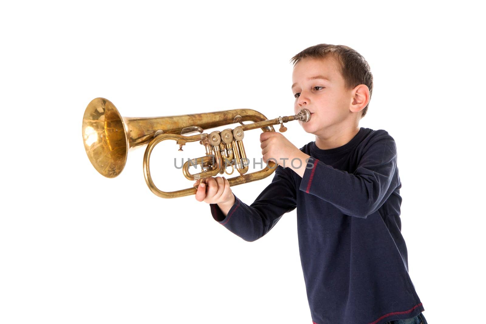 young boy blowing into a trumpet against white background
