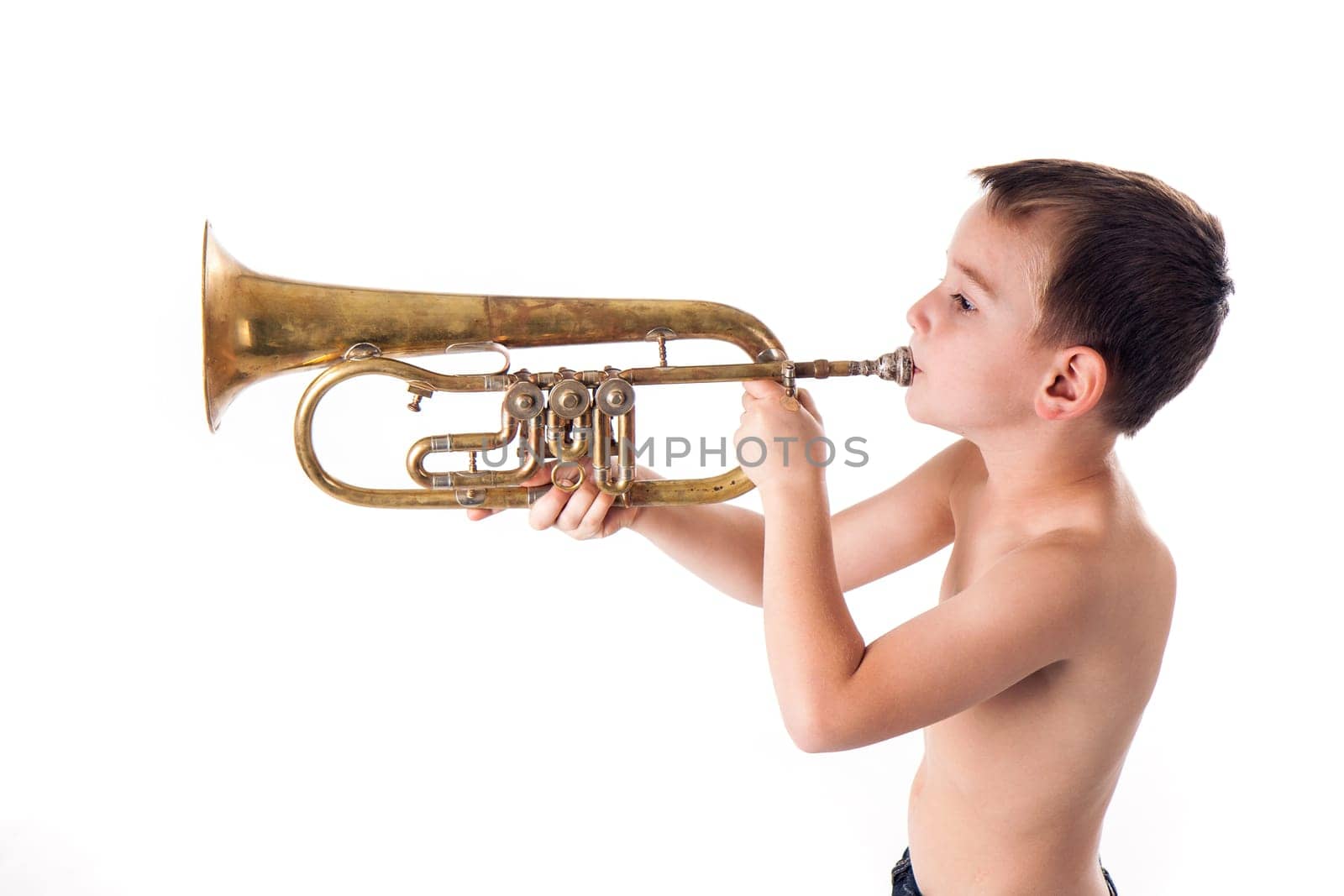 young boy blowing into a trumpet against white background
