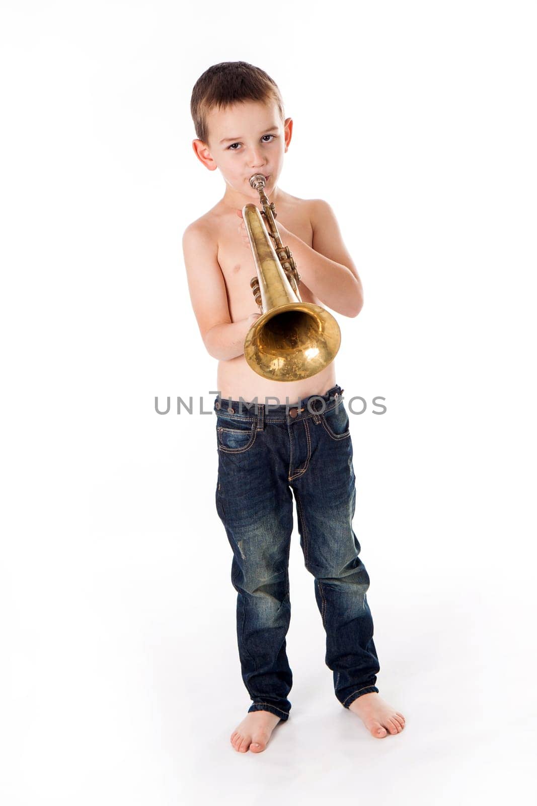 young boy blowing into a trumpet against white background