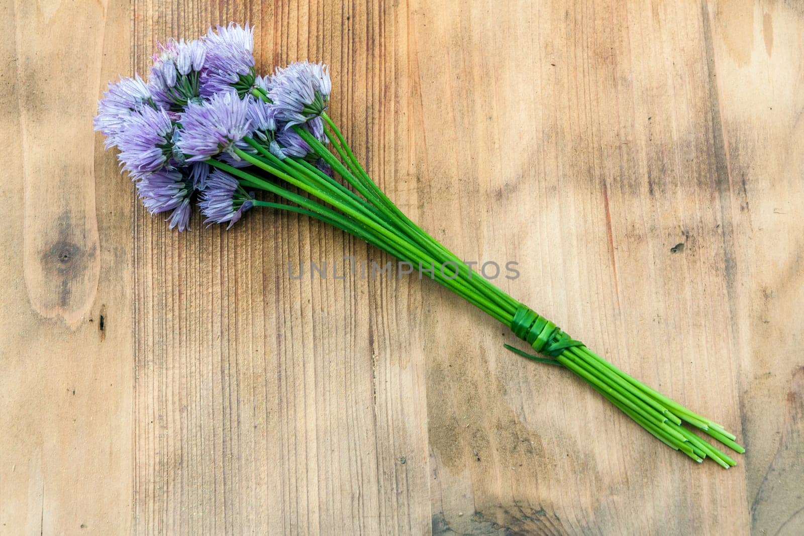 Flower chives tied in a snop on a natural wooden cutting board