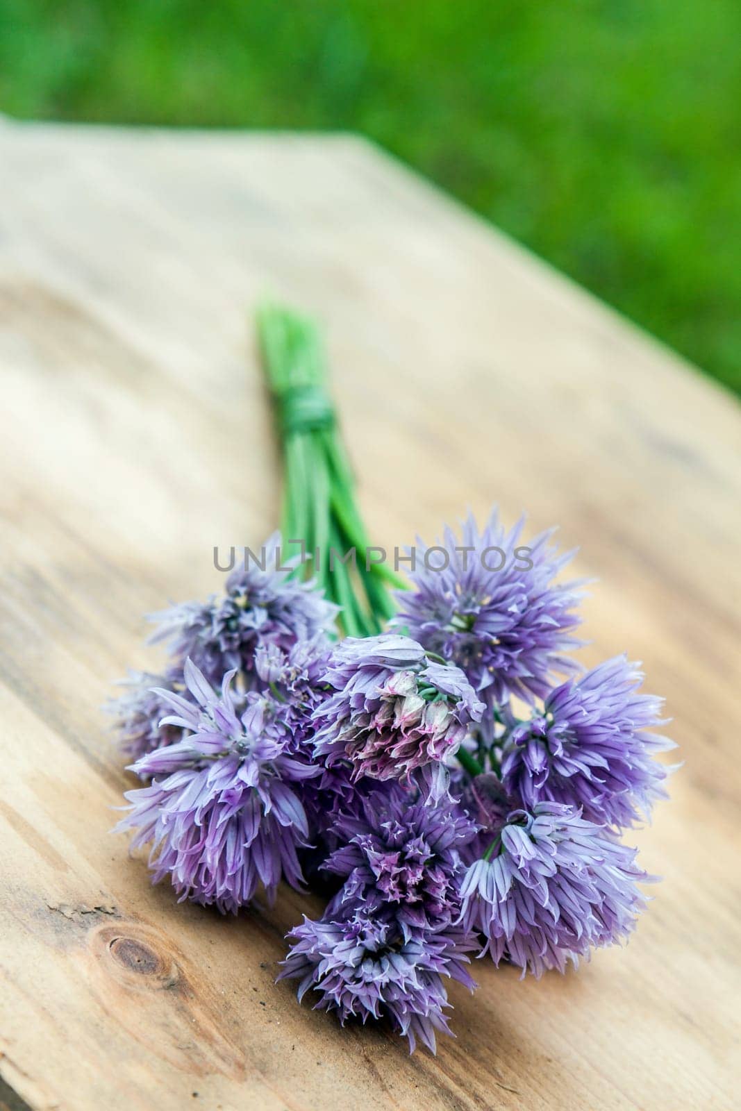 Flower chives tied in a snop on a natural wooden cutting board
