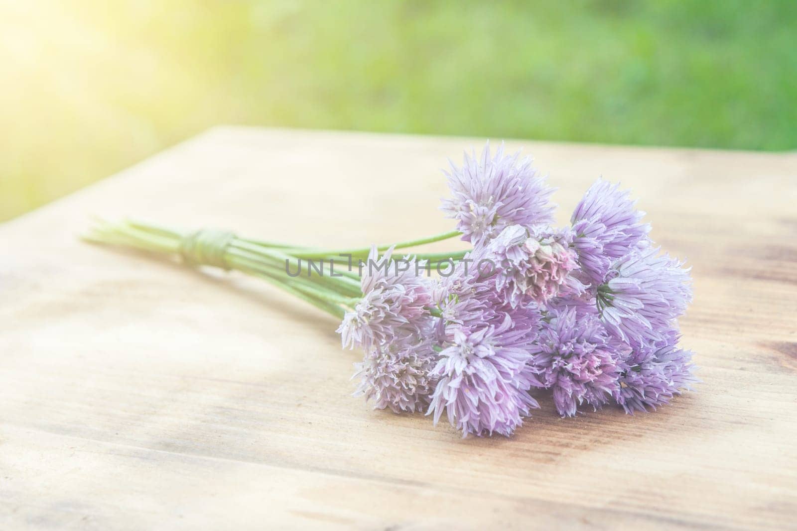 Flower chives tied in a snop on a natural wooden cutting board
