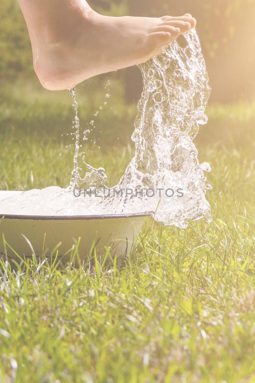 Little boy and splash of water in the summer garden