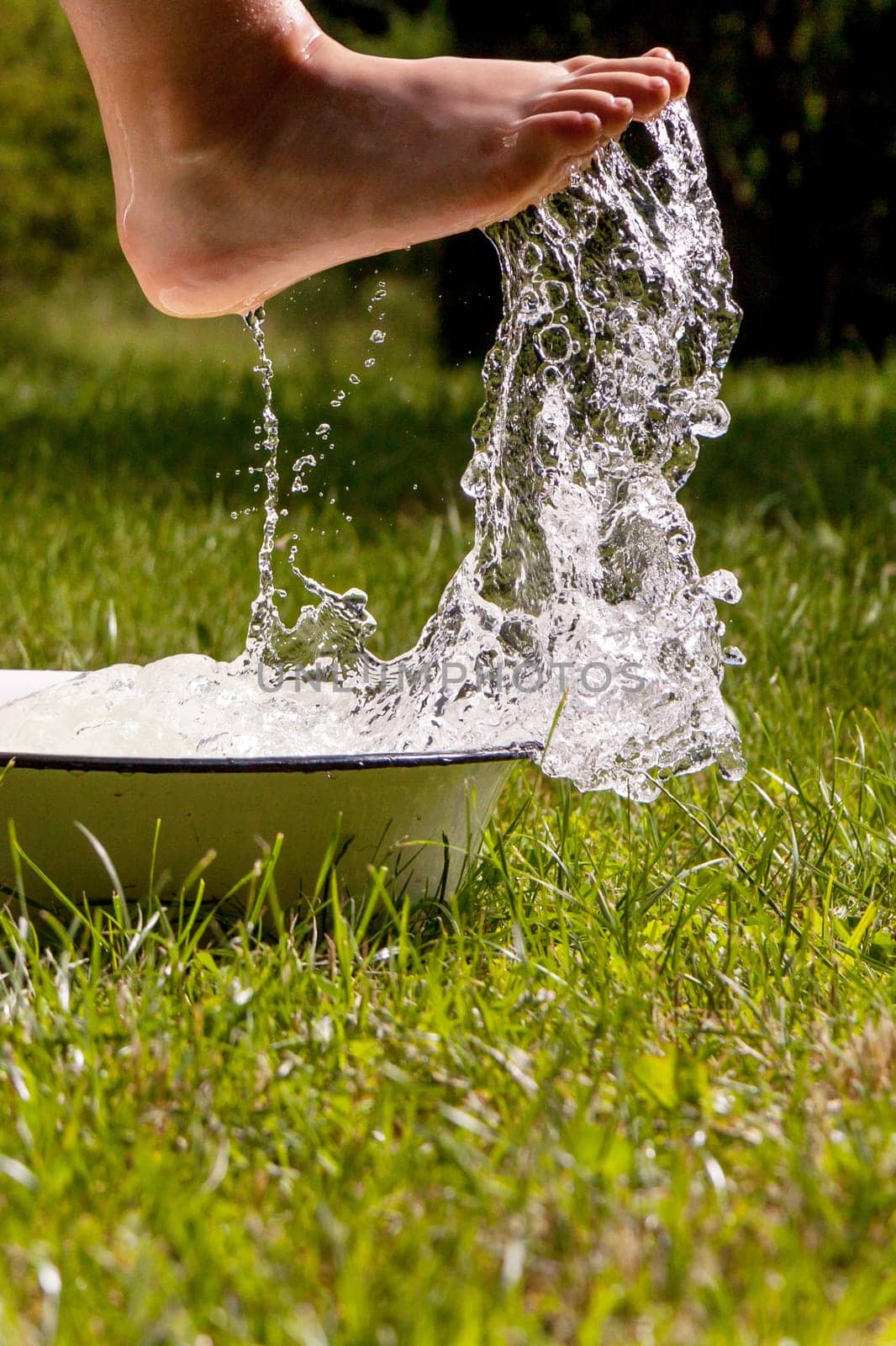 Little boy and splash of water in the summer garden